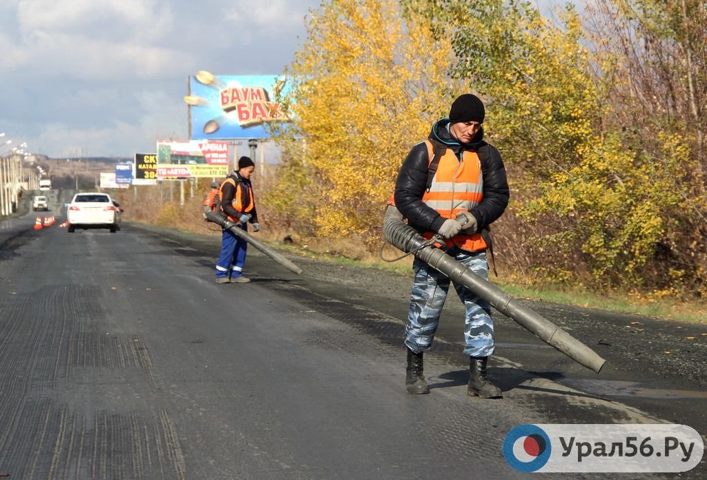 Рабочие разгоняют лужи с дороги, на которую планируется укладывать асфальт. Орск, Никельская объездная, 14.10.19