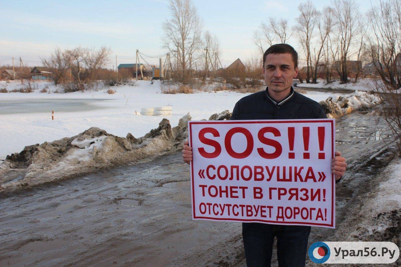 Председатель СНТ «Соловушка + Лайф» Денис Поляков с плакатом на фоне зимней переправы