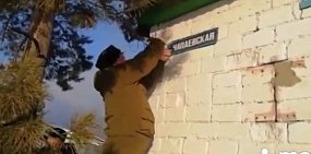 Один из казаков демонтирует указатель улицы Чапаевская