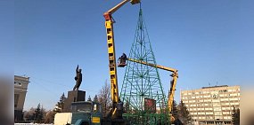 Рабочие устанавливают звезду на макушку елки